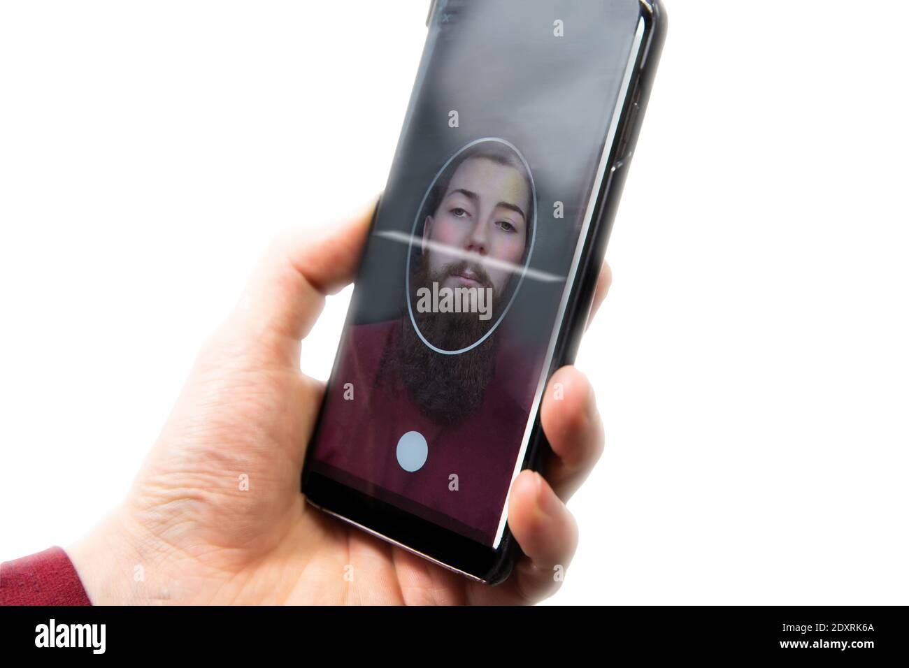 Giovane maschio che tiene il telefono cellulare per la scansione del viso, per cambiare faccia a un altro volto tecnologia e falso, concetto isolato su sfondo bianco Foto Stock