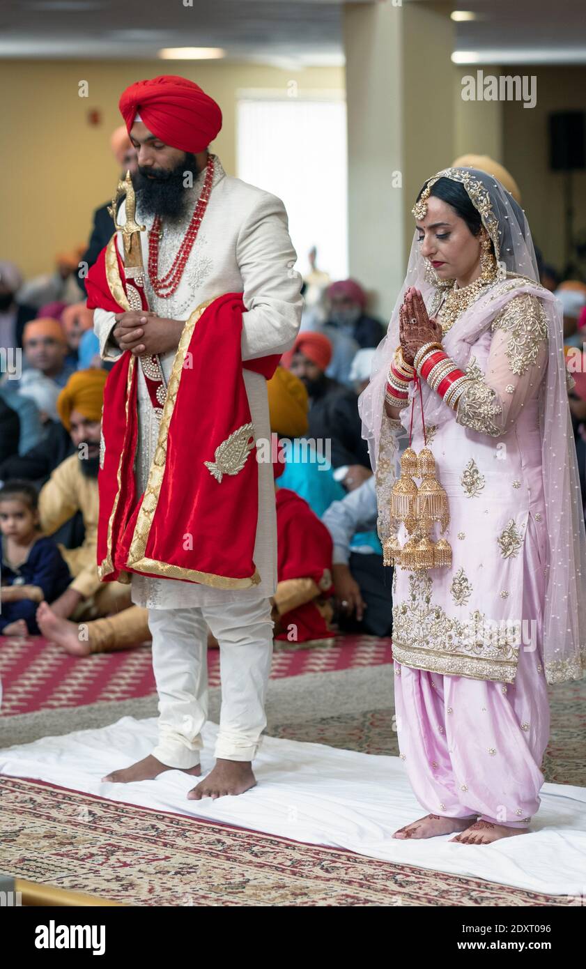 Gli sposi e gli sposi di un servizio di nozze Sikh pregano e meditano. A Queens, New York City. Foto Stock