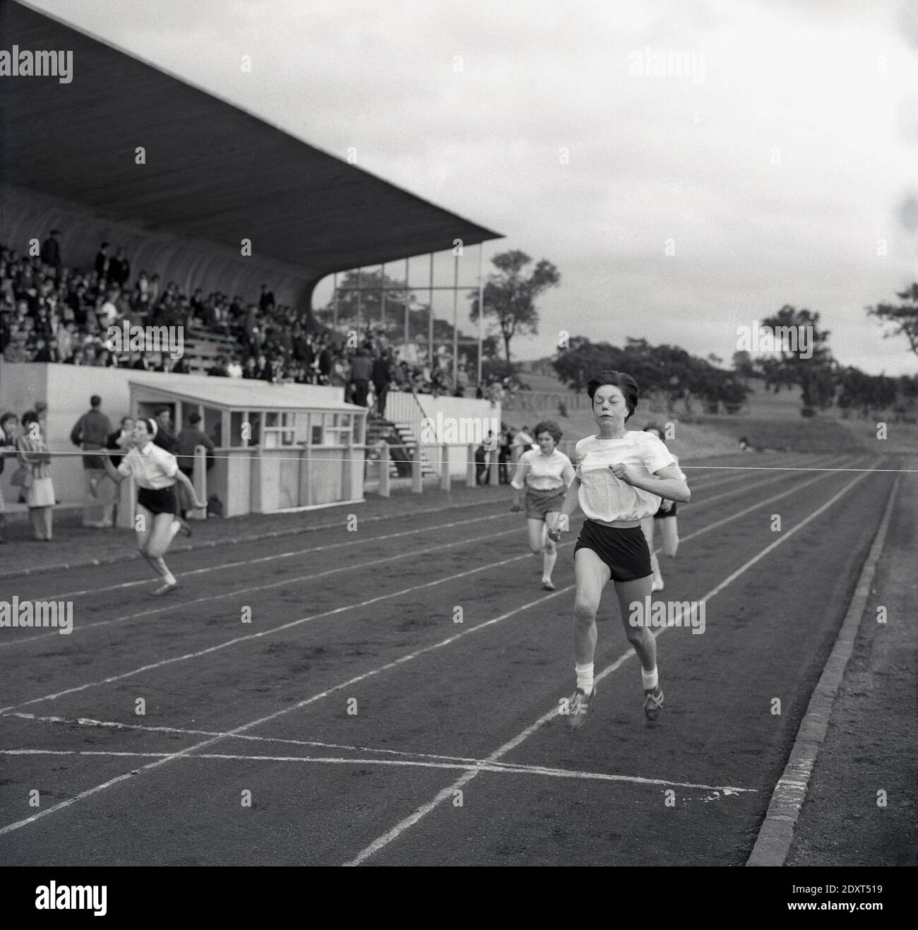 Anni '1960, studentesse storiche che gareggiano in una gara su una pista da corsa di ceneri in una giornata sportiva della contea, Fife, Scozia. Foto Stock