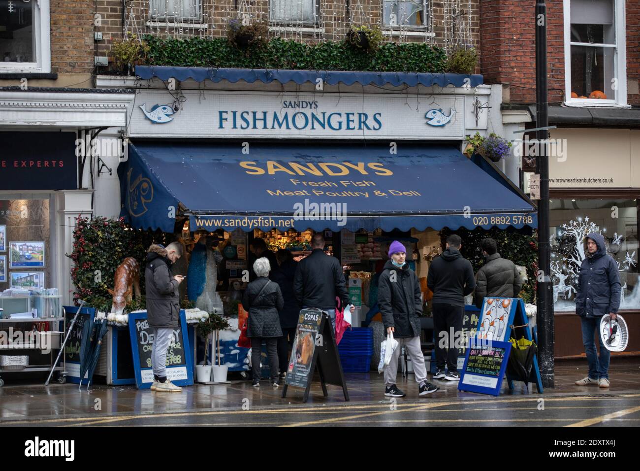 Code di acquirenti si schierano per raccogliere le loro forniture natalizie al di fuori di un pescivendoli locale a Twickenham, Richmond, Inghilterra, Regno Unito Foto Stock