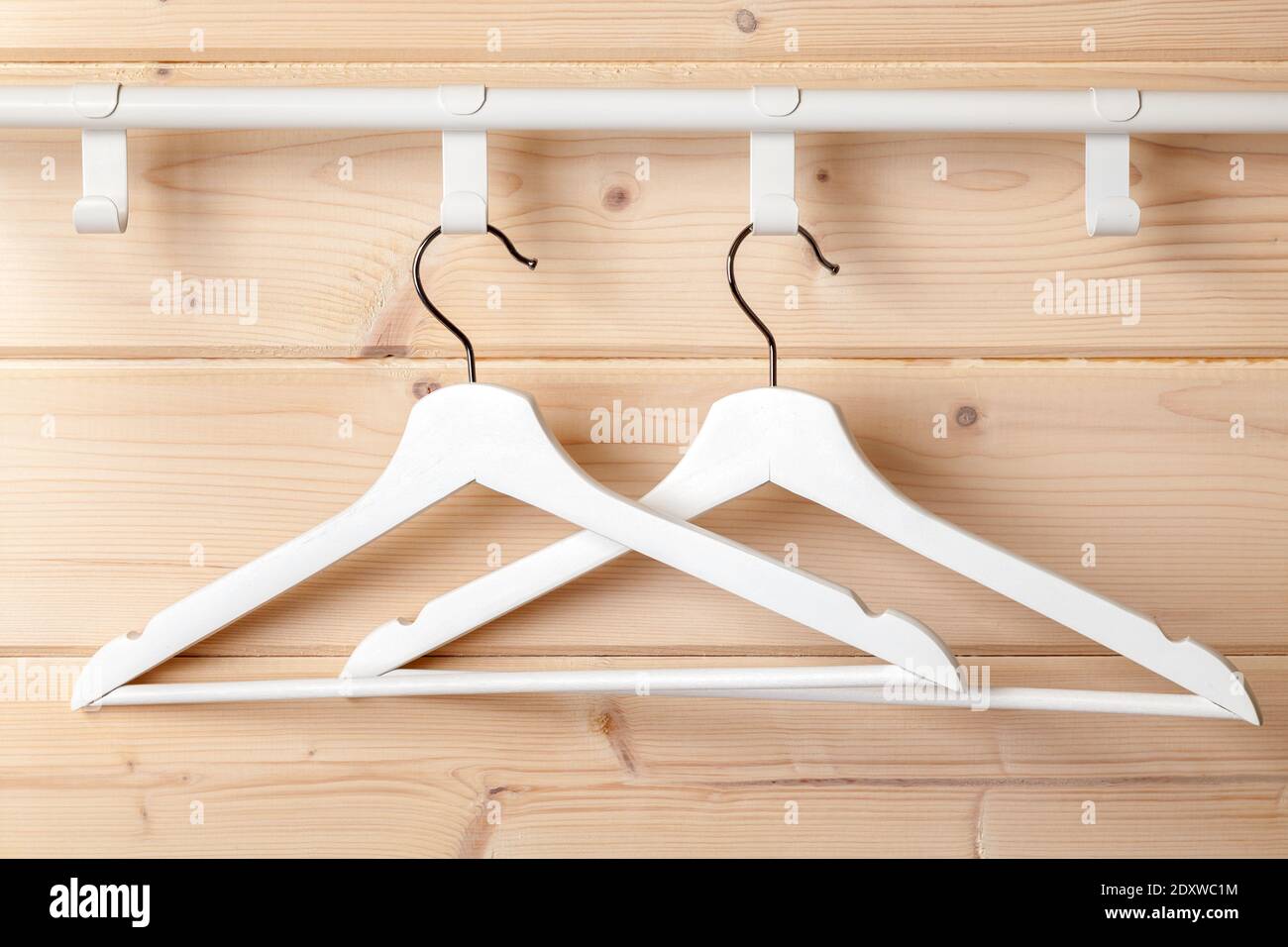 Due appendiabiti bianchi standard sono appesi vicino a pareti in legno naturale, foto ravvicinata Foto Stock