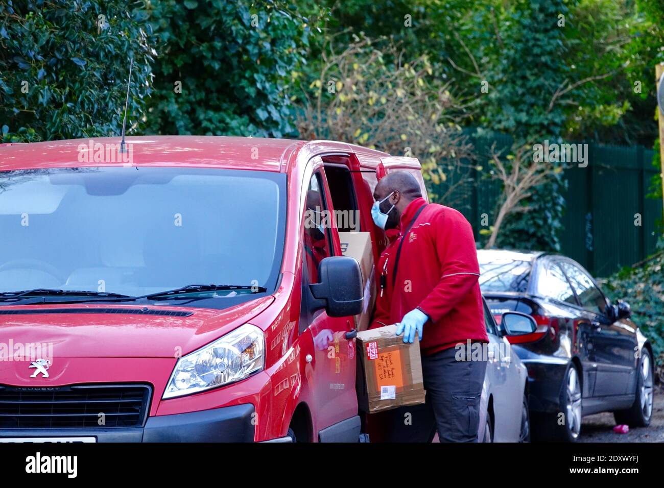 Royal Mail postino caricamento furgone post rosso con pacchi per le consegne del regalo di Natale la vigilia di Natale. Hampstead Royal Mail Delivery Office, Londra. Foto Stock