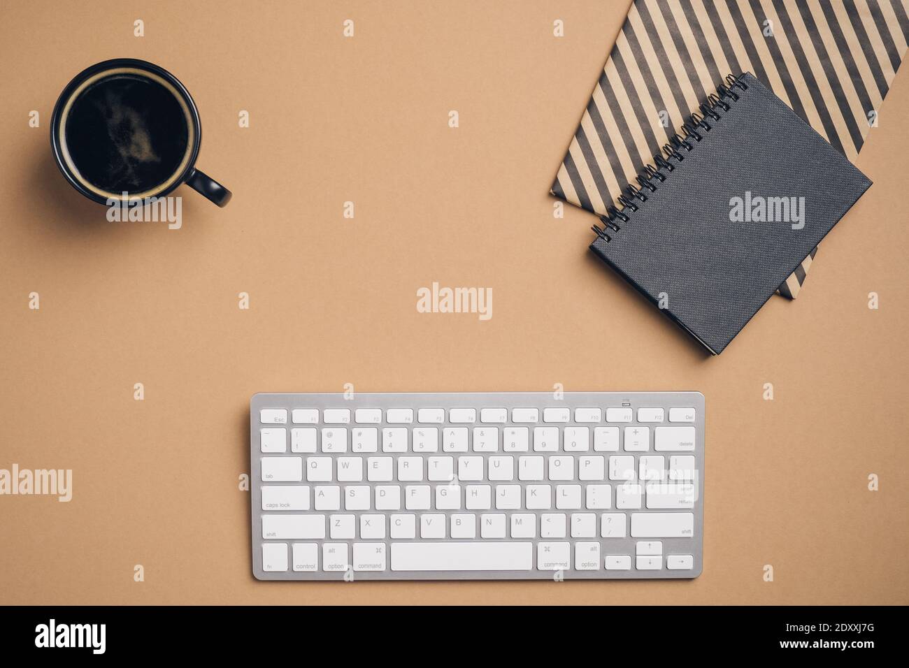 Moderno tavolo da lavoro con tastiera per computer, notebook di carta, tazza di caffè su sfondo marrone. Elegante spazio di lavoro femminile. Disposizione piatta, vista dall'alto. Foto Stock