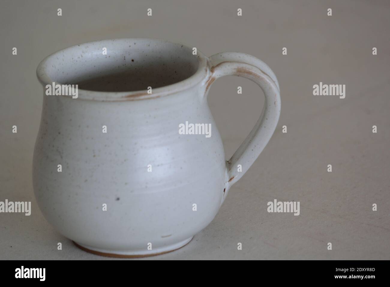 Un primo piano di una caraffa in ceramica bianca su un grigio sfondo Foto Stock