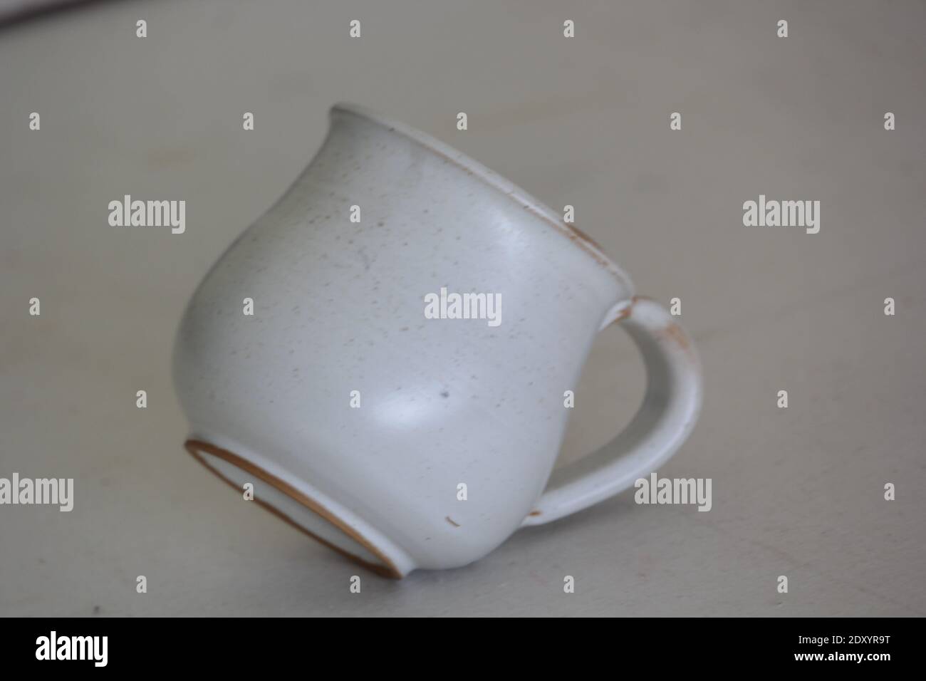 Un primo piano di una tazza di ceramica bianca su un grigio sfondo Foto Stock
