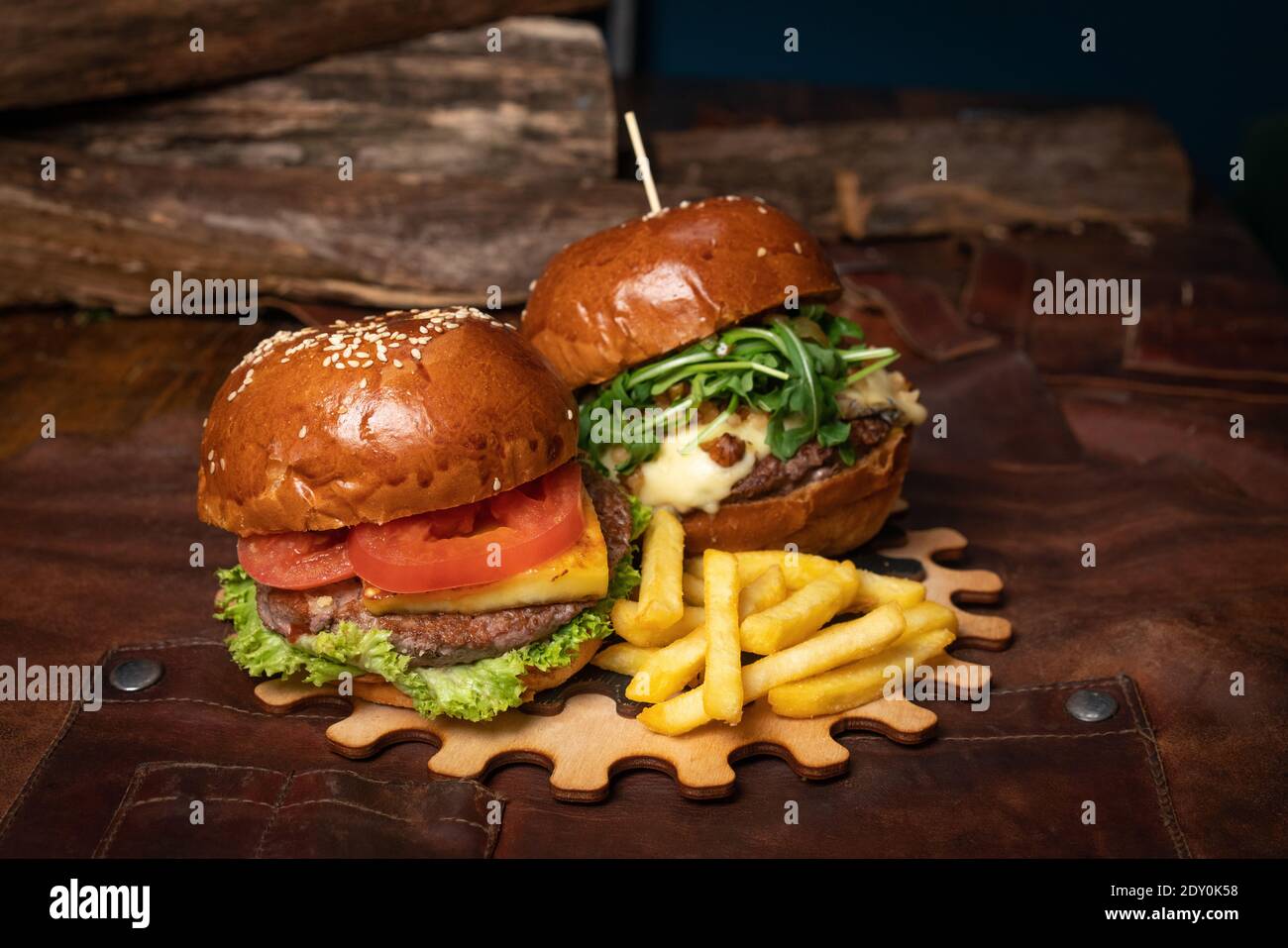 Una doppia porzione di hamburger di manzo fresco e una con noci fritte sono servite su una parte decorativa in legno di un semplice meccanismo. Concetto di ristorante Foto Stock
