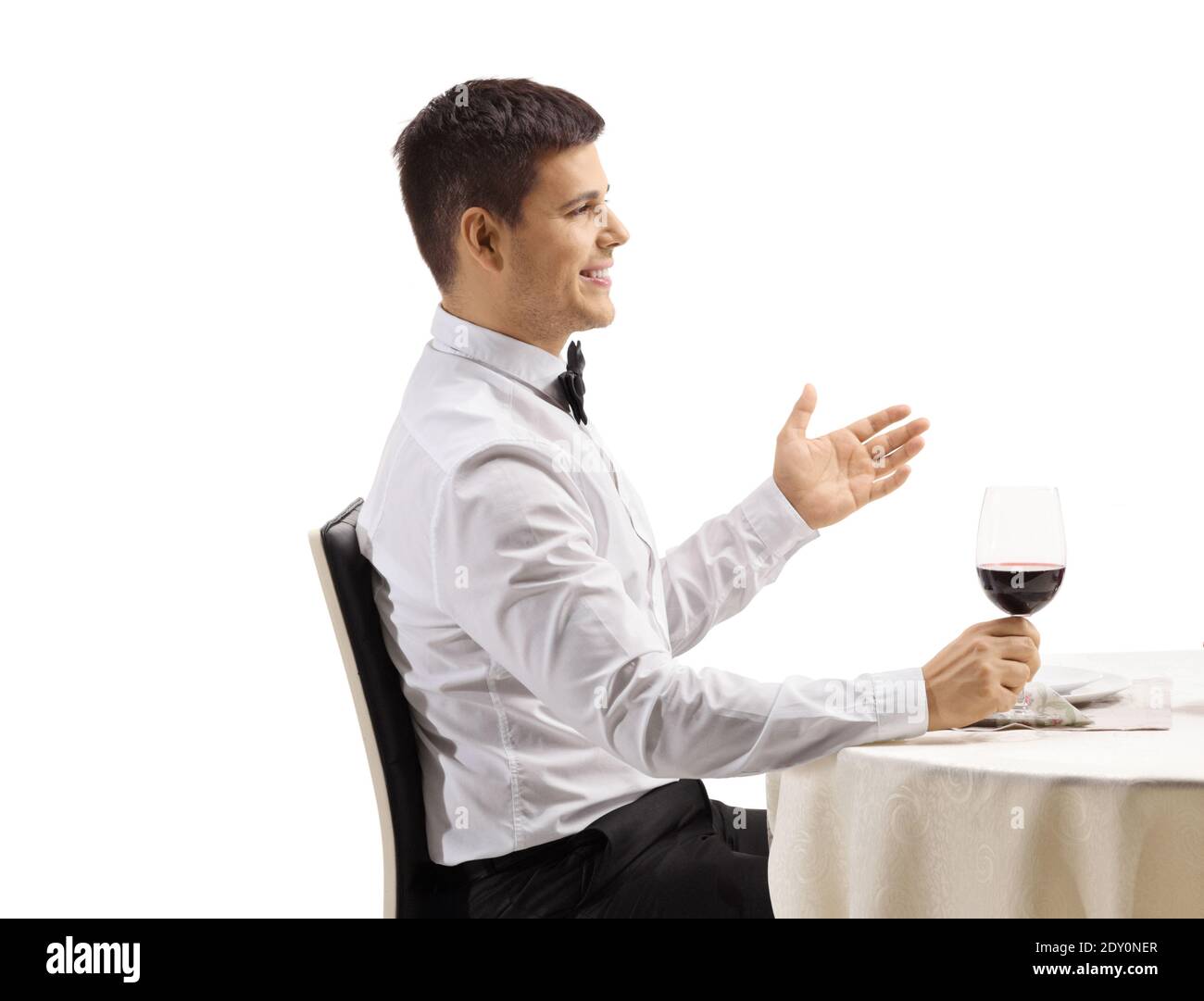 Elegante giovane uomo che parla ad un tavolo da ristorante isolato sopra sfondo bianco Foto Stock