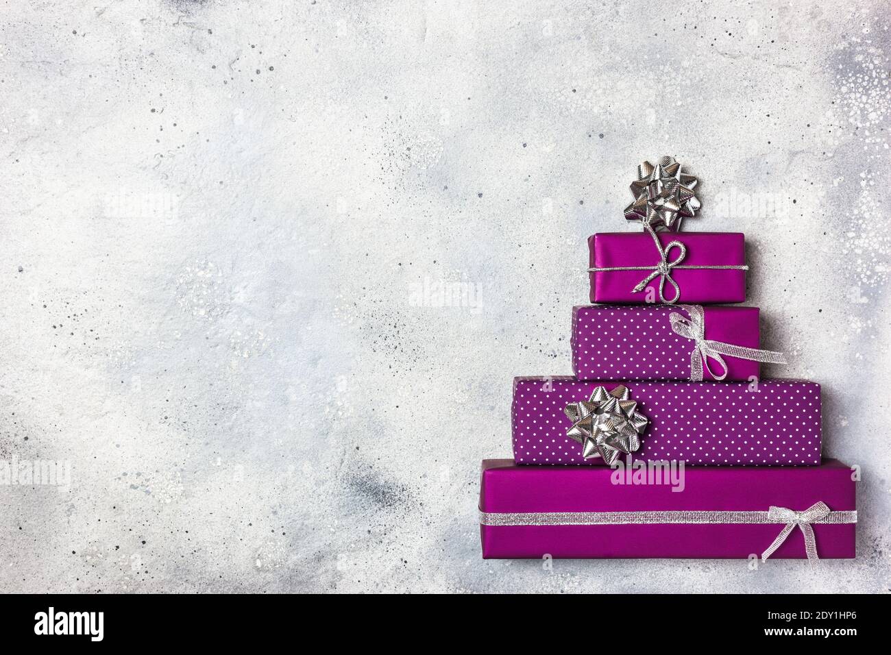 Albero di Natale fatto di scatole di regali viola, composizione piatta di posa. Concetto di vacanza invernale. Biglietto d'auguri di Natale creativo. Foto Stock