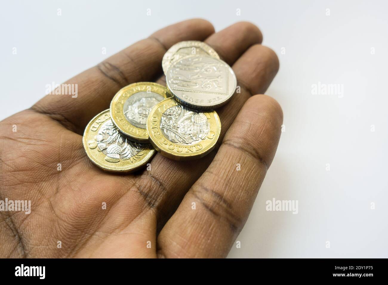 Uomo asiatico che offre una manciata di monete inglesi Foto Stock