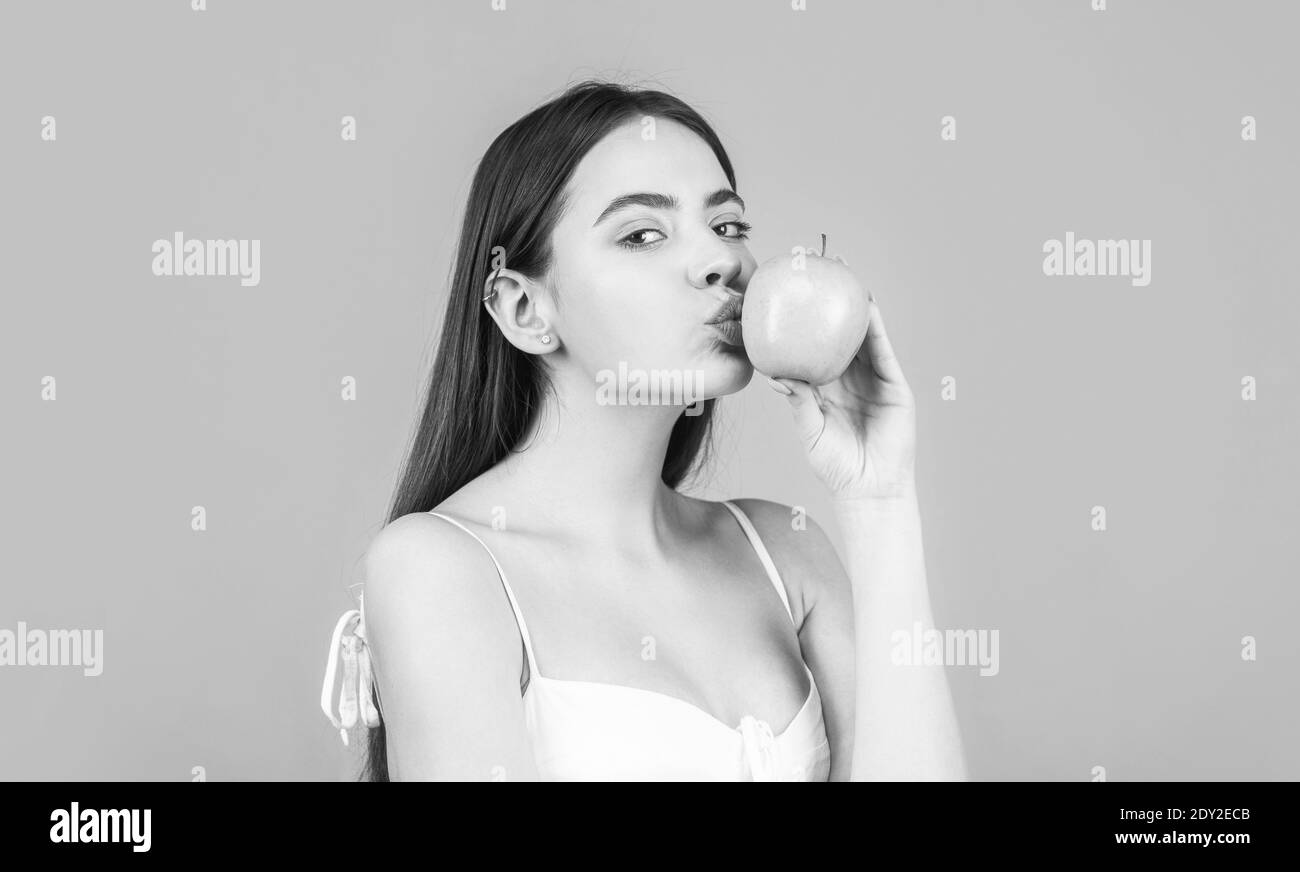 Bella giovane donna che mangia una mela. Stile di vita sano. Felice donna bacio mela su sfondo blu. Bianco e nero Foto Stock