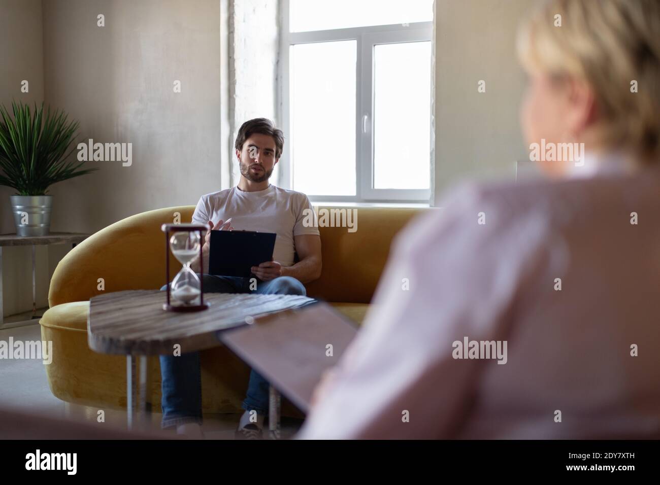 Uomo bearded che condivide i pensieri con il consulente offuscato e che attingeva sopra appunti durante il test di psicoterapia durante l'appuntamento in salute mentale clinica Foto Stock