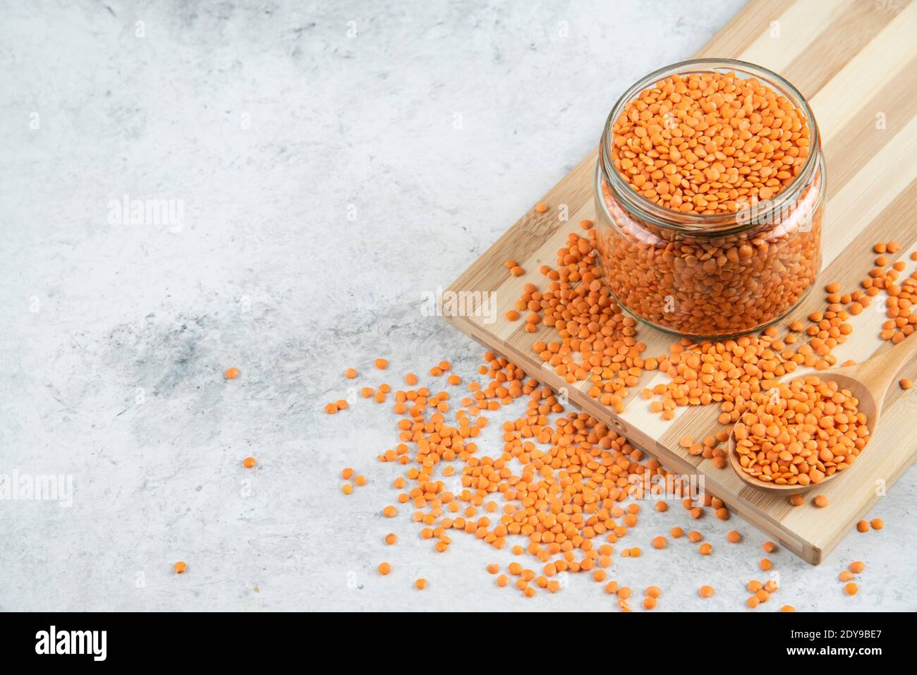 Vaso di vetro di lenticchie rosse su tavola di legno Foto Stock