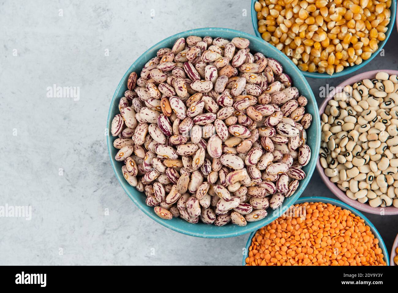 Mazzetto di vari fagioli, cornetti e lenticchie rosse non cotti sulla superficie del marmo Foto Stock