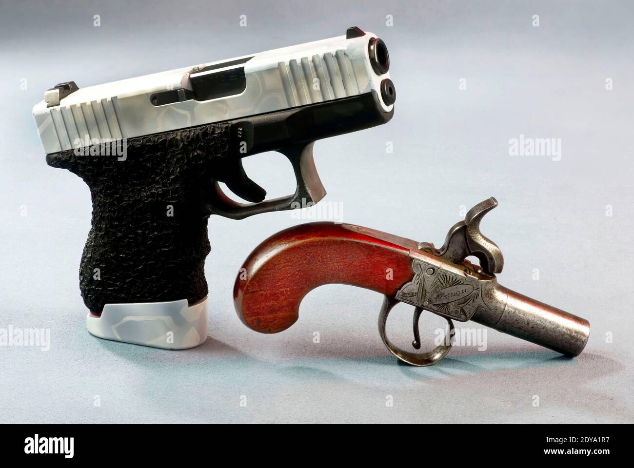 Vecchia scuola e nuove pistole scuola, una con 40 calibro semi auto e cappello e palla antico. Foto Stock