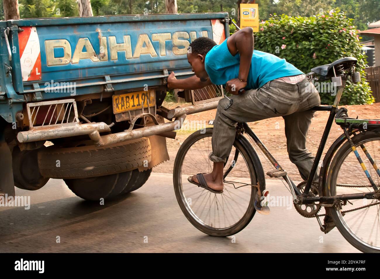 Sulle strade del Ruanda, le persone in bicicletta spesso si agganciano alla parte posteriore di un camion, per coprire grandi distanze velocemente e lavorare gratuitamente. Foto Stock