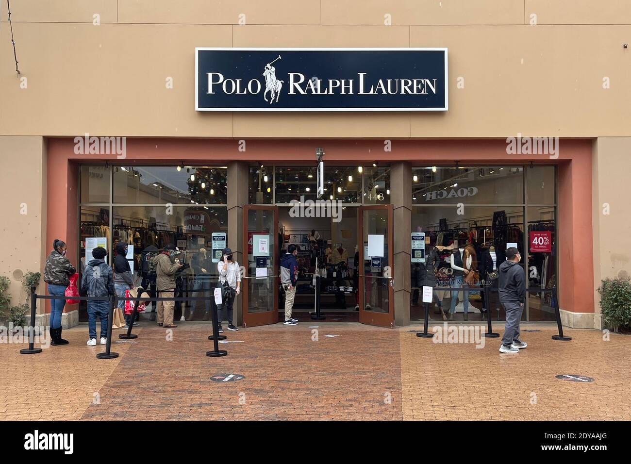 La gente si trova in fila fuori dal negozio Polo Ralph Lauren il giorno prima di Natale presso la Cittadella Outles in mezzo al coronavirus globale COVID-19 pandemia, Foto Stock