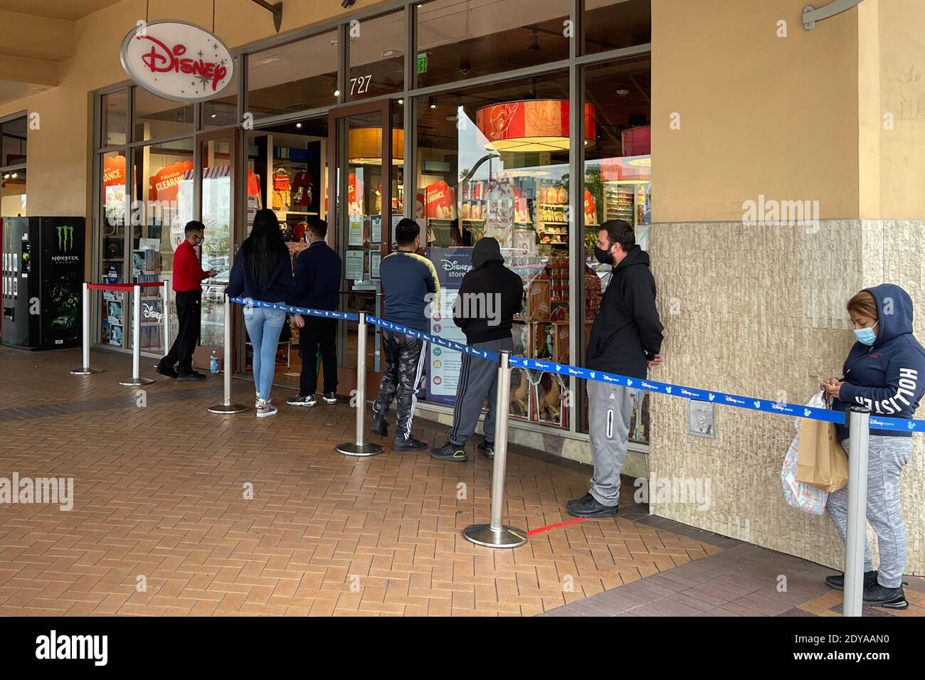 La gente si trova in fila fuori dal negozio Disney il giorno prima di Natale presso la Cittadella Outles in mezzo al coronavirus globale COVID-19 pandemia, Giovedi, Foto Stock