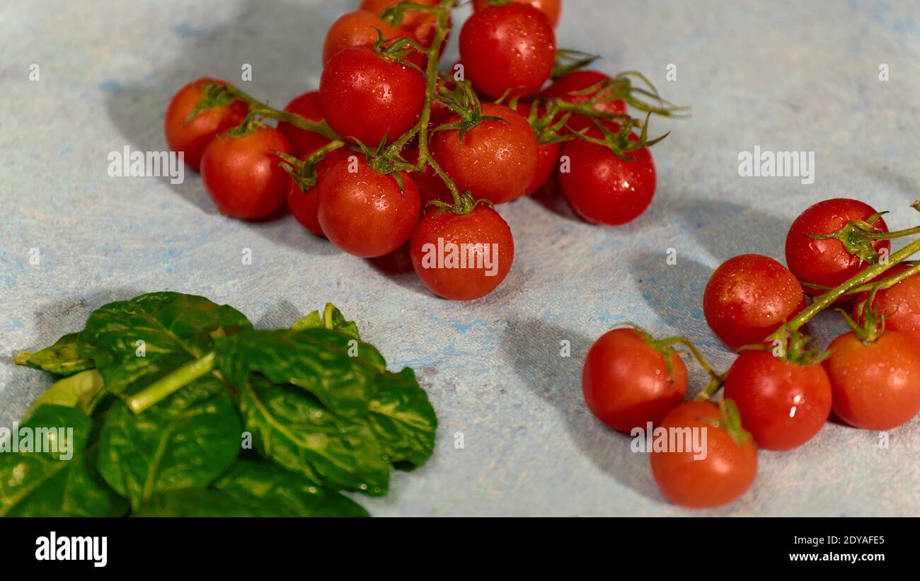 Pomodori d'uva freschi con foglie di spinaci su sfondo bianco dipinto a mano. Vegan vegies dieta alimentare. Erbe, pomodori rossi, concetto di cucina. Foto Stock