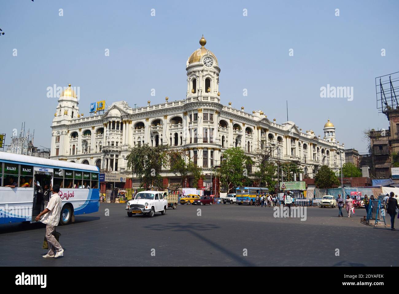 Kolkata, India - Marzo, 2014: Veicoli e persone al bivio di fronte al Metropolitan Building in Esplanade. Casa storica con torre dell'orologio in hi Foto Stock
