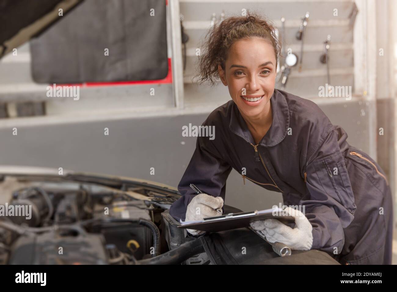 Ritratto felice lavoratore africano americano donna lavoro per meccanico auto in garage controllo motore auto. Foto Stock