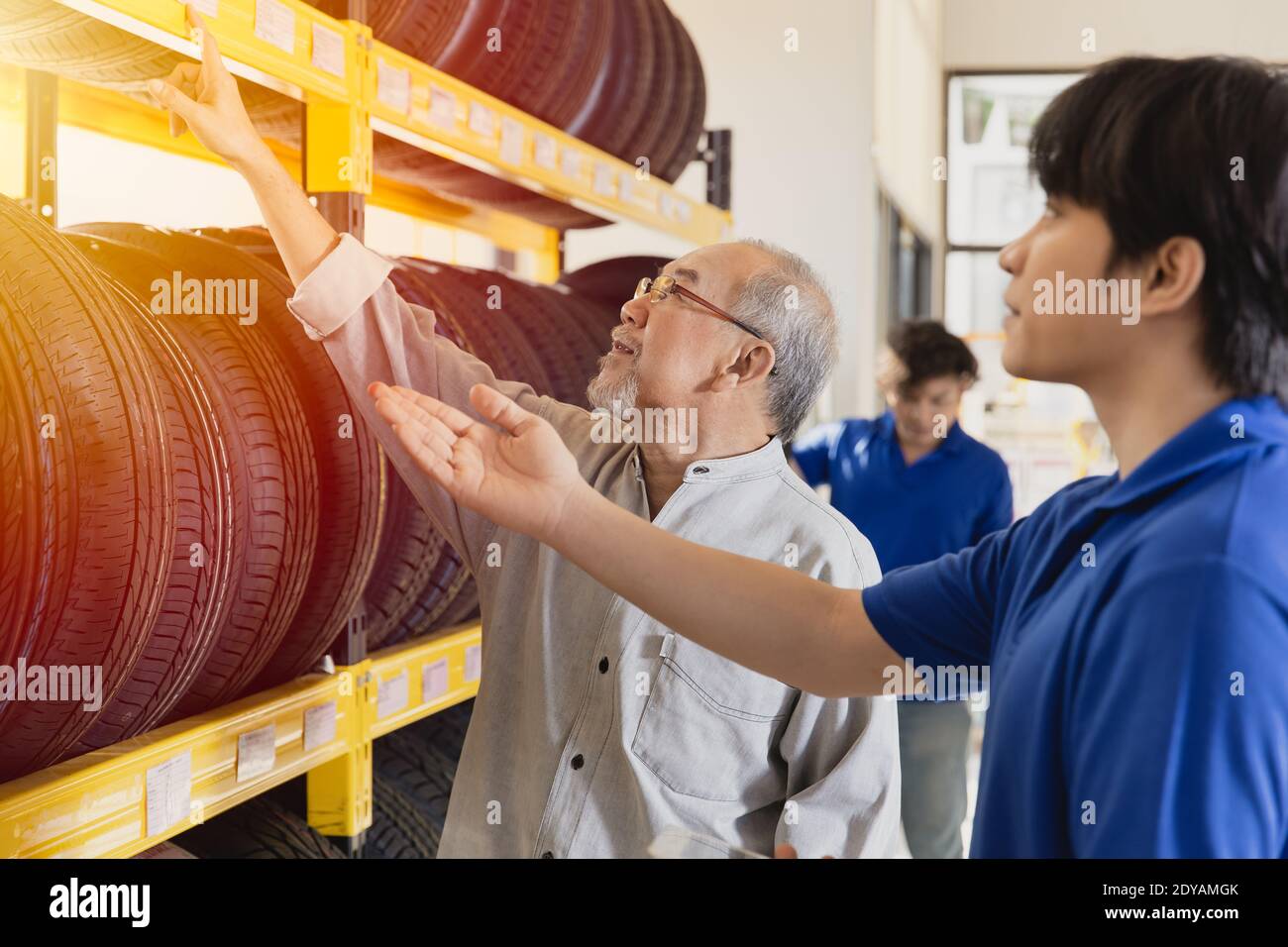 Il cliente sceglie pneumatici auto in garage e lo staff di vendita consiglia vari tipi di pneumatici del veicolo Foto Stock