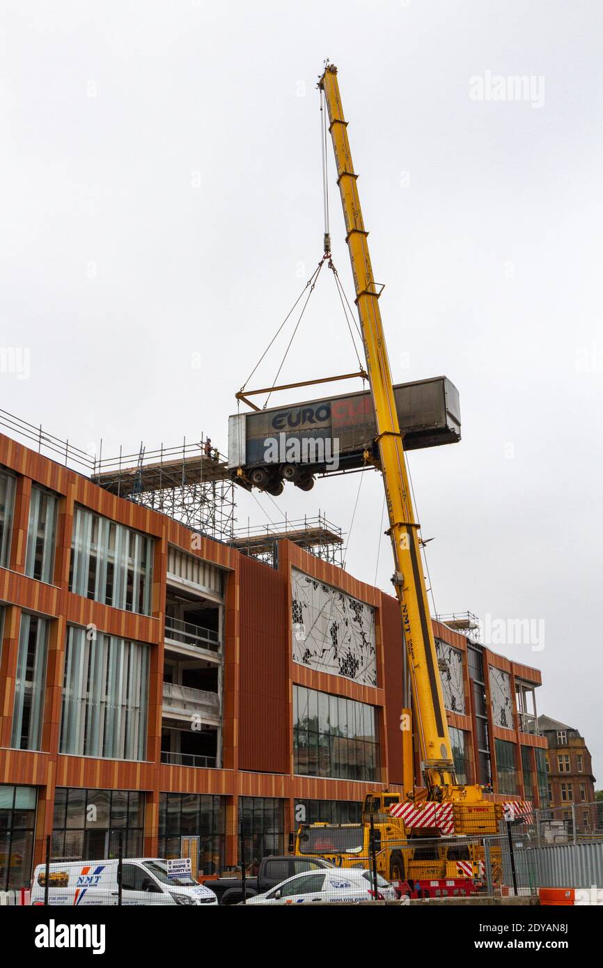 Una gru mobile che solleva il rimorchio di un autocarro articolato fino a una rampa che sale su un edificio in costruzione a Nottingham, Notts, Regno Unito. Foto Stock