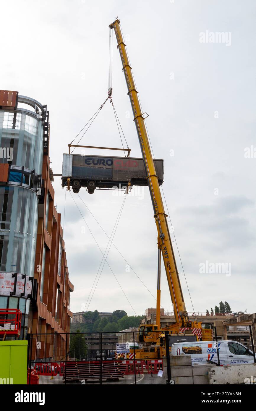 Una gru mobile che solleva il rimorchio di un autocarro articolato fino a una rampa che sale su un edificio in costruzione a Nottingham, Notts, Regno Unito. Foto Stock