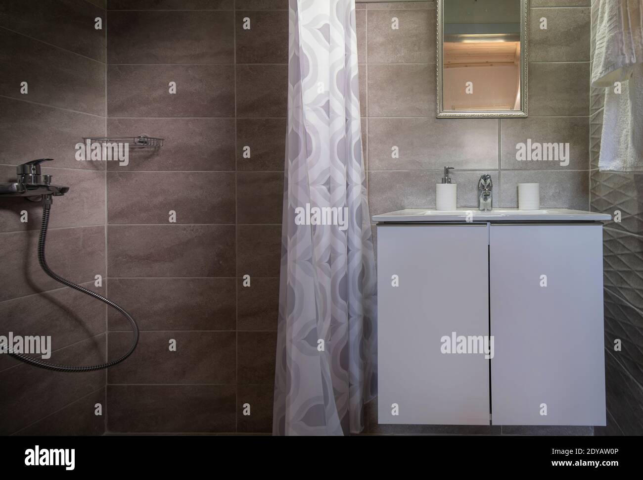 Guardaroba di piccolo bagno con doccia e lavabo bianco. Vista frontale dell'interno del gabinetto in piastrelle di ceramica grigia di stile moderno Foto Stock
