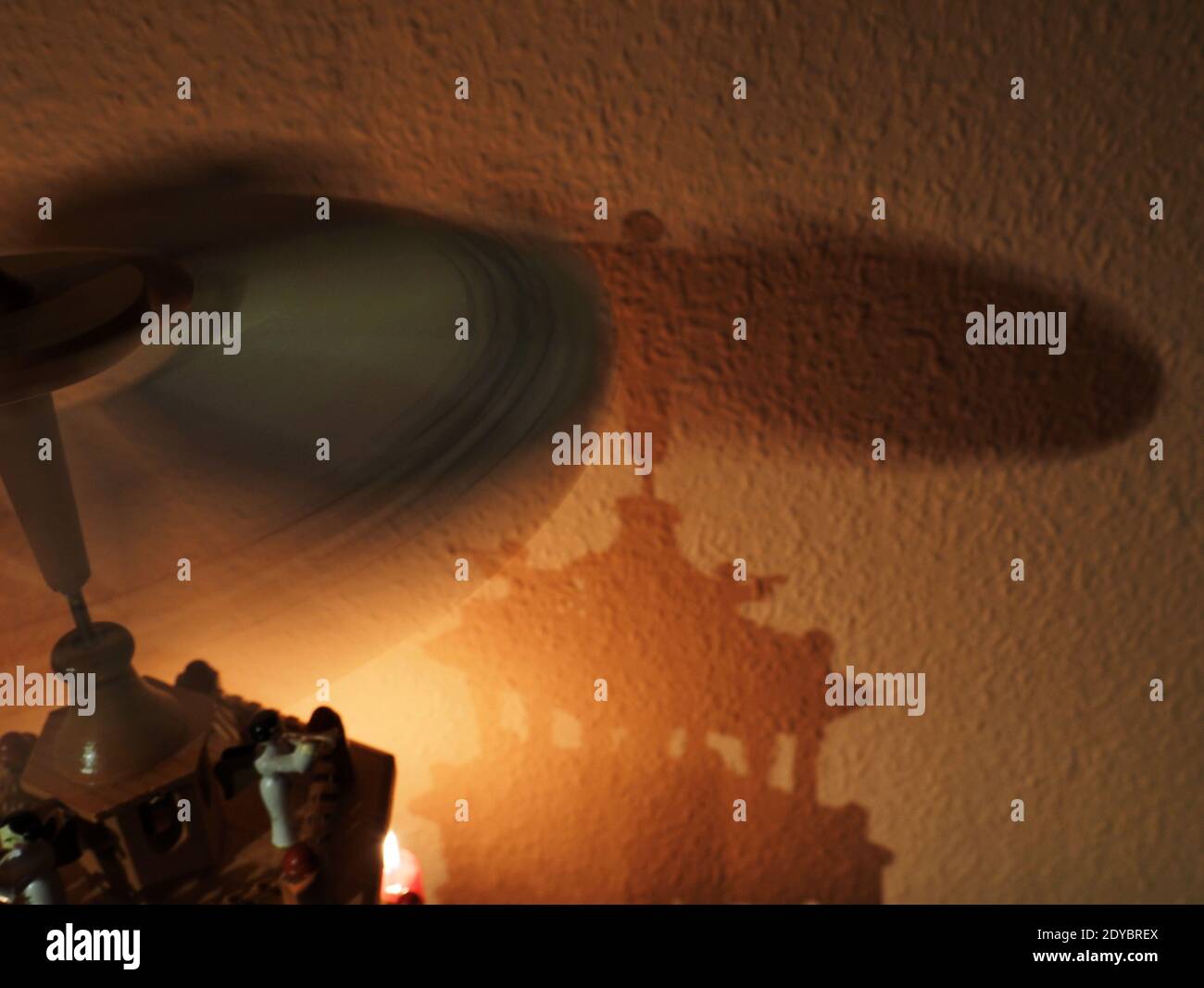 Weimar, Germania. 23 dicembre 2020. L'ombra di una piramide di Natale sulla parete coperta con carta da parati Ingrain e candele brucianti creano un'atmosfera natalizia. Credit: Soeren Stache/dpa-Zentralbild/ZB/dpa/Alamy Live News Foto Stock