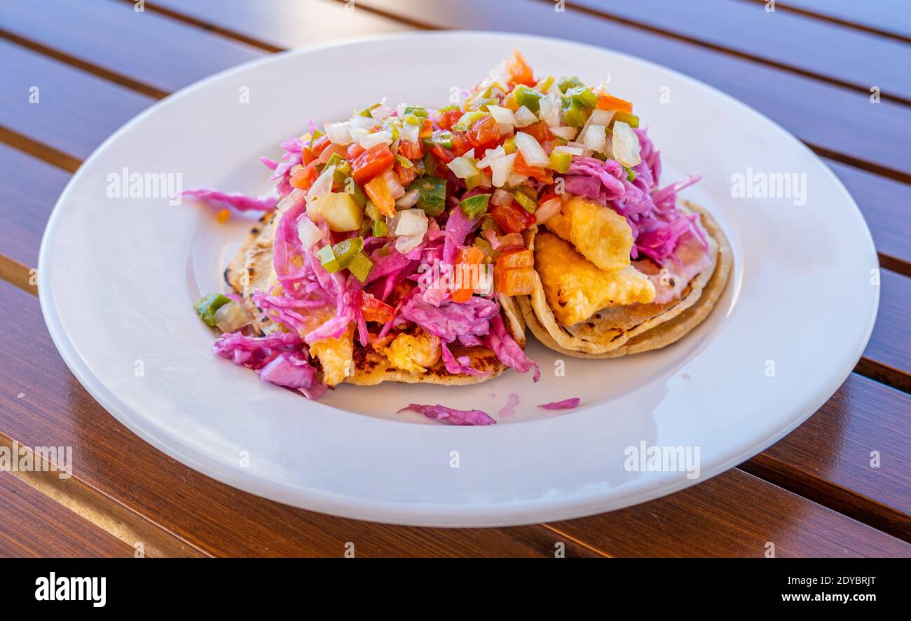 Red Snapper Fish Tacos su piatto bianco e tavolo in legno Foto Stock