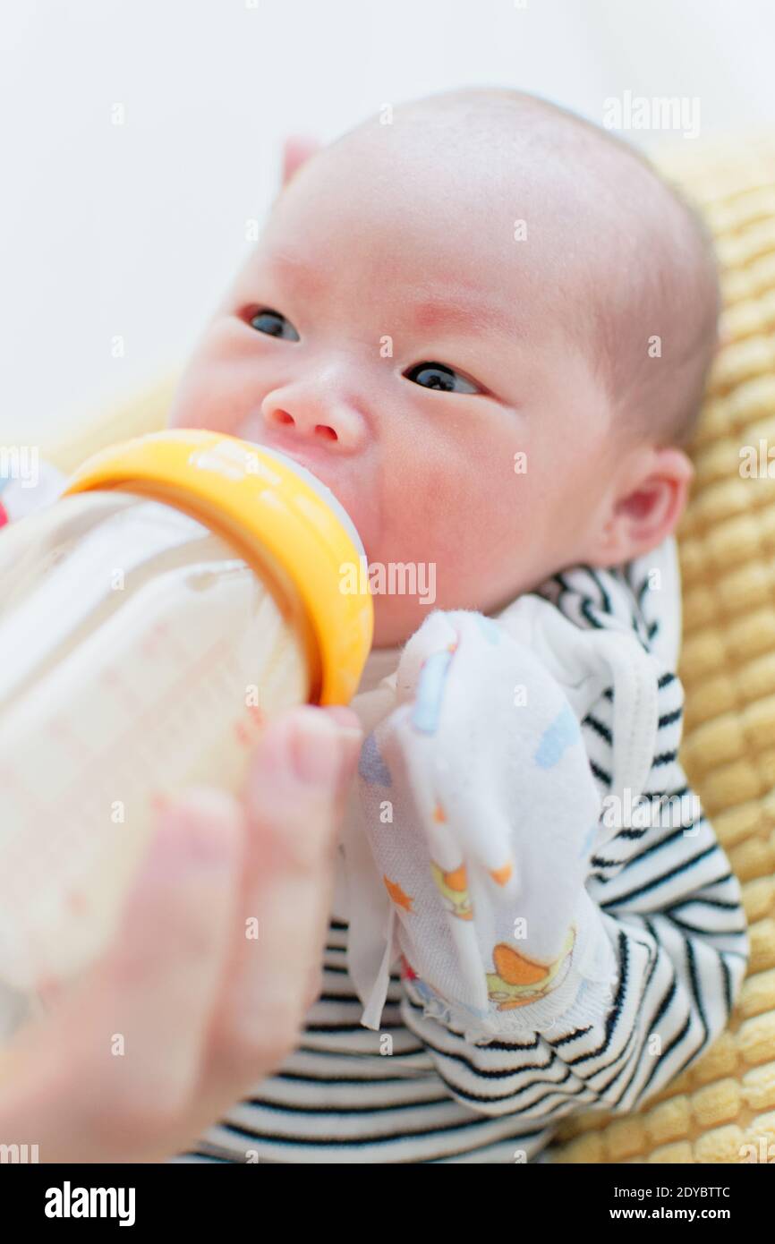 Nutrire la bambina cinese di meno di un mese con latte di formula da un biberon. Foto Stock