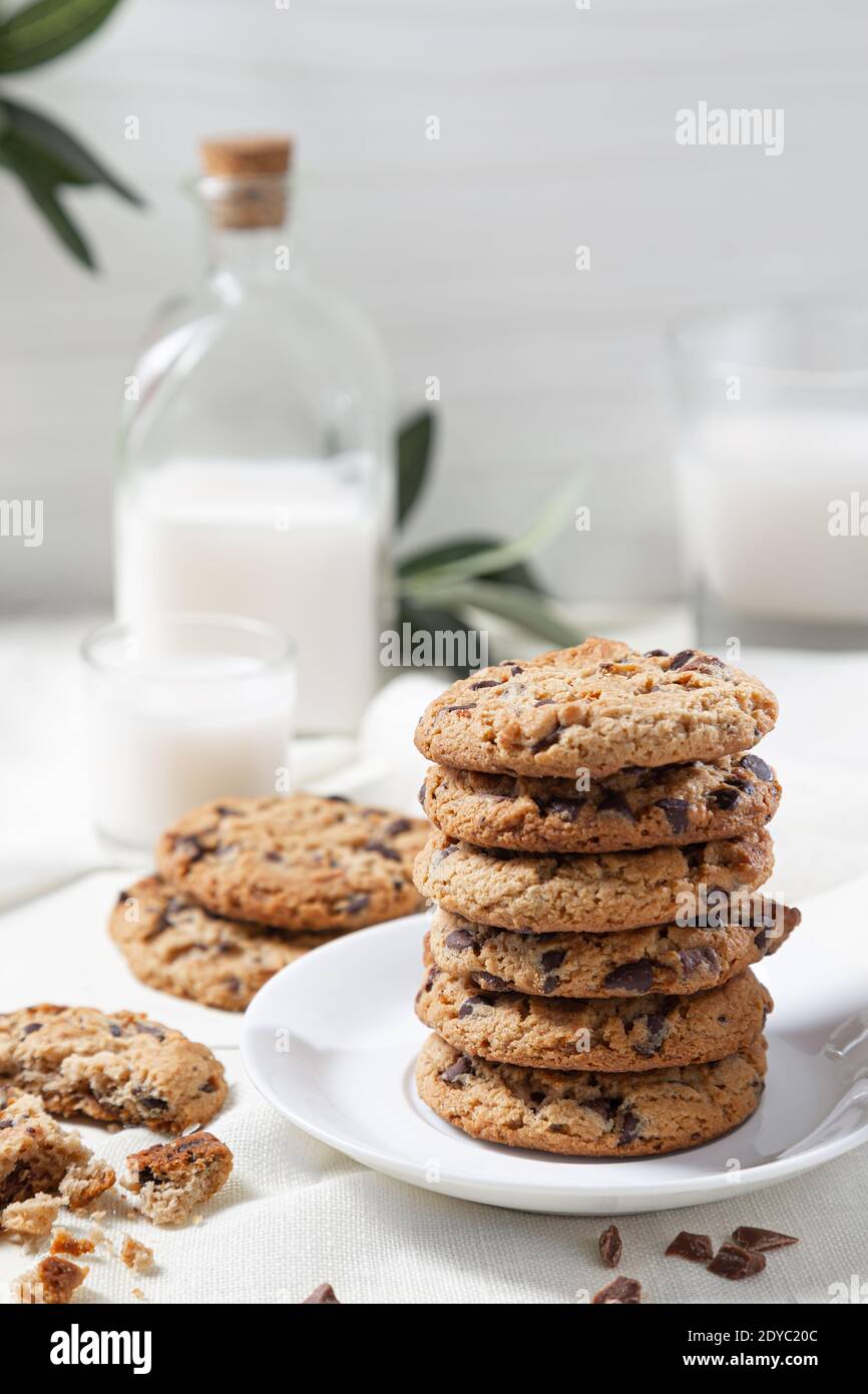 Biscotti al cioccolato e latte su sfondo bianco di legno. Concetto di cibo dolce. Foto Stock