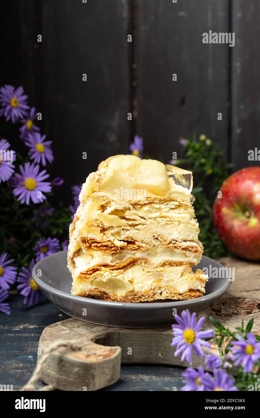 Un pezzo di torta Napoleone su tavola di legno al buio sfondo rustico Foto Stock