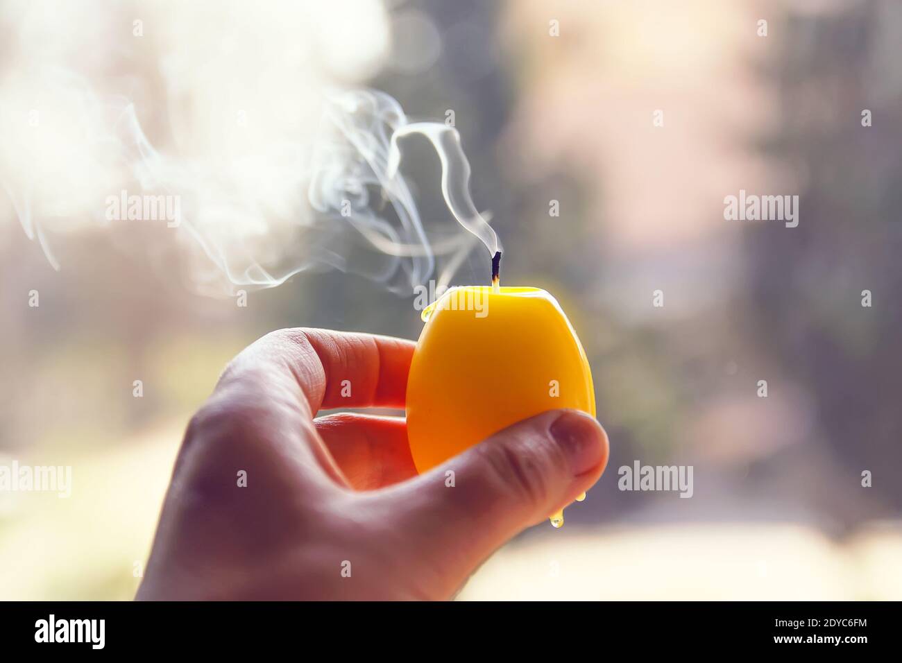 Candela estinta con fumo in una mano su sfondo natura sfocato. Foto Stock