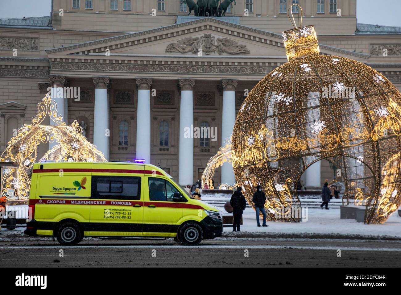 Mosca, Russia. 25 dicembre 2020 un'ambulanza corre lungo una strada nel centro di Mosca sullo sfondo della facciata del teatro Bolshoi alla vigilia di Capodanno, in Russia Foto Stock