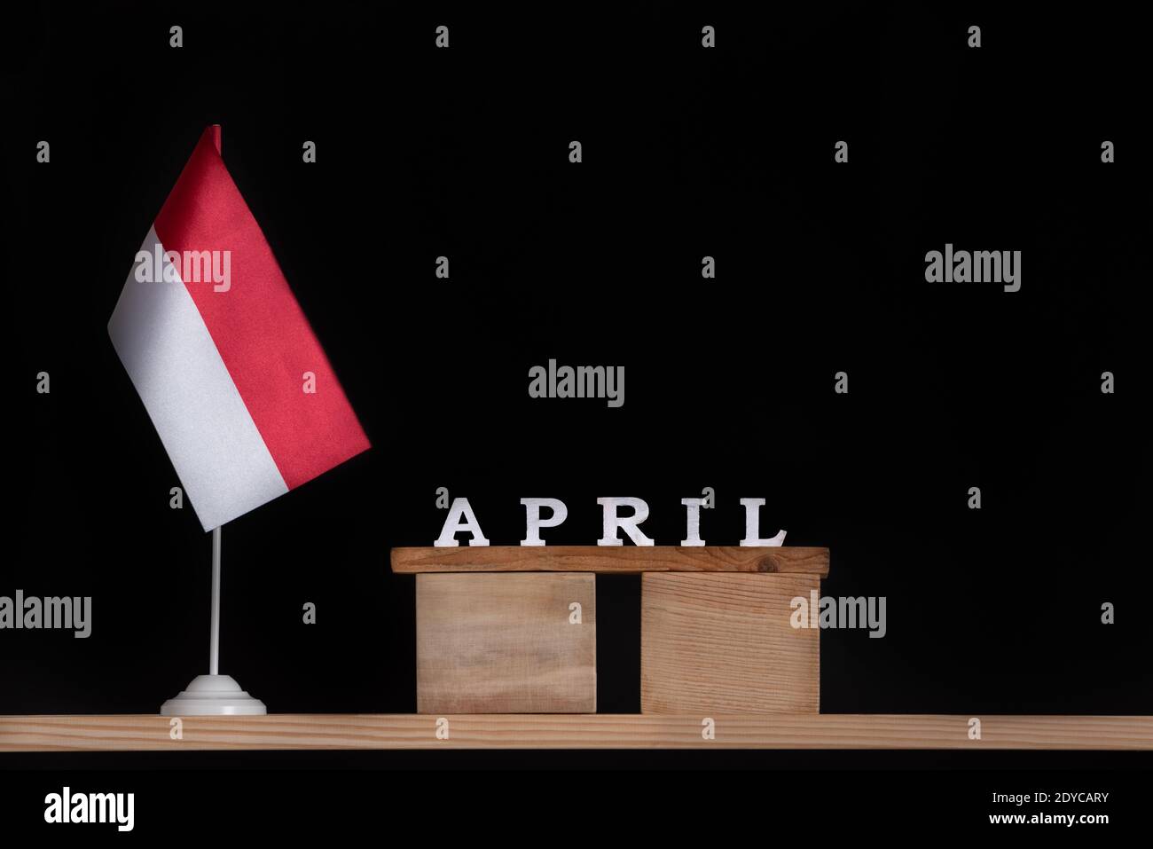 Calendario in legno di aprile con bandiera polacca su sfondo nero. Vacanze della Polonia nel mese di aprile Foto Stock