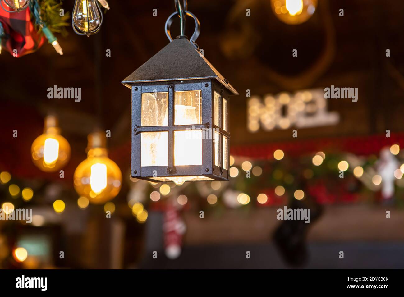 Fuoco selettivo di bella lampada a forma di capanna con illuminato testo in bulbo e noel scritto in sfondo sfocato nel ristorante Foto Stock