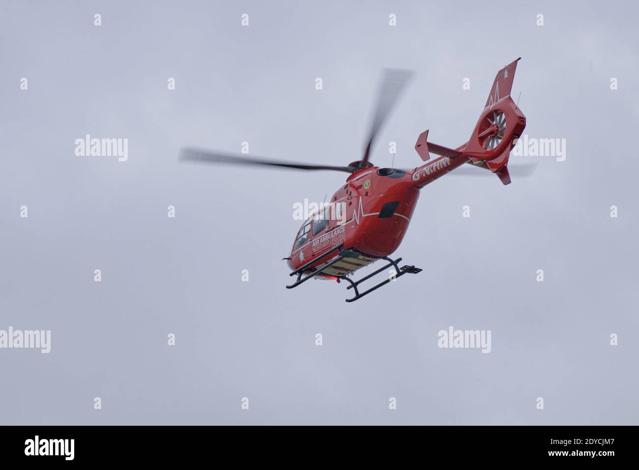 Irlanda del Nord Red Emergency Air Ambulance Helicopter volare via con un paziente a bordo Foto Stock