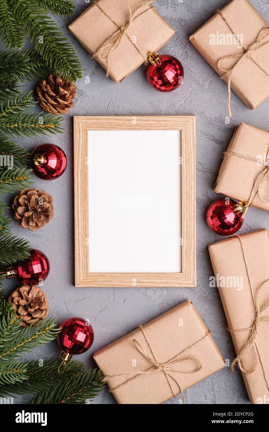 Natale vacanze composizione con immagine mockup cornice. Baubles rossi, regali e rami di abete. Foto Stock