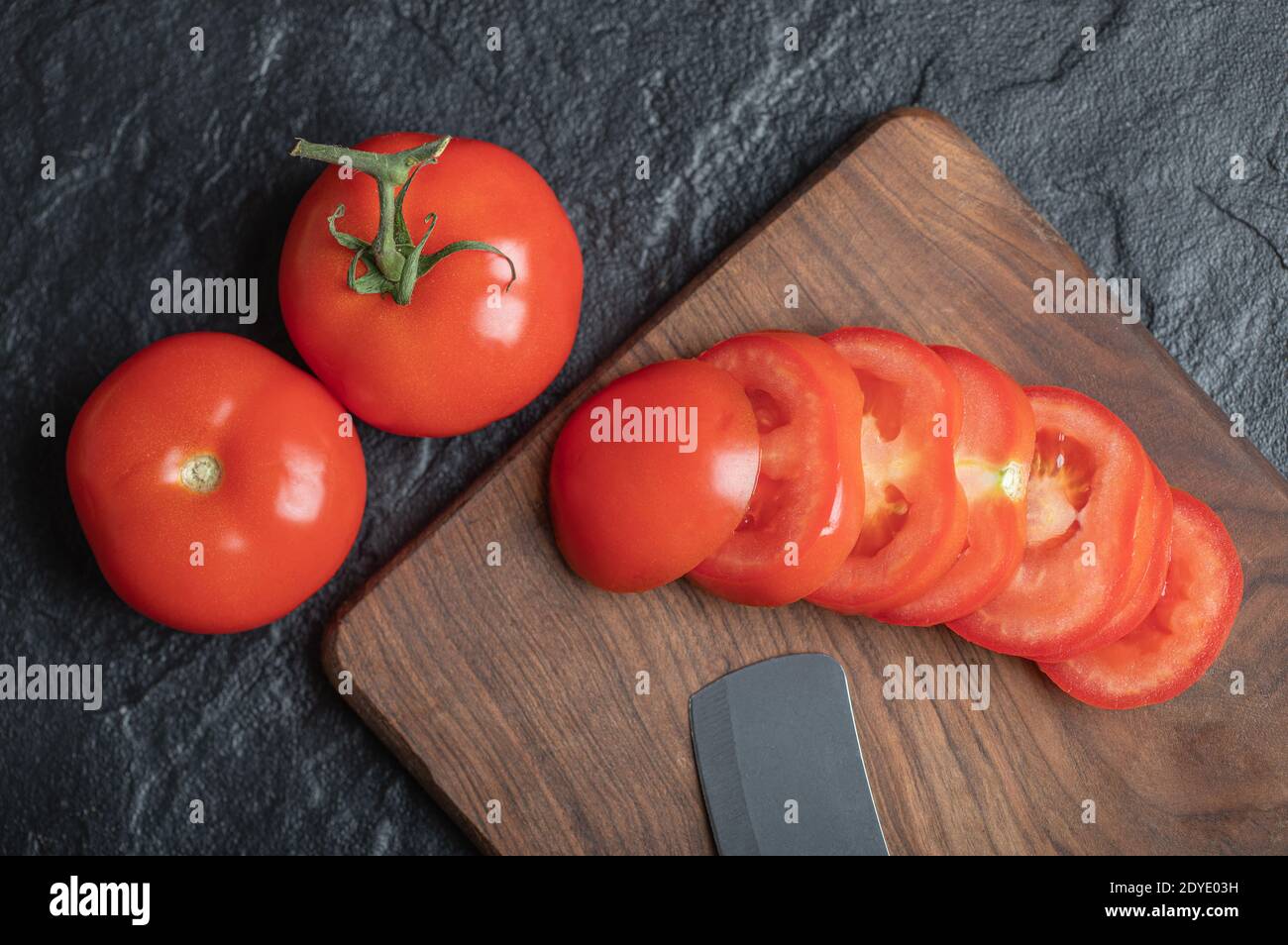 Vista ravvicinata dei pomodori appena raccolti e succosi su sfondo di pietra scuro Foto Stock