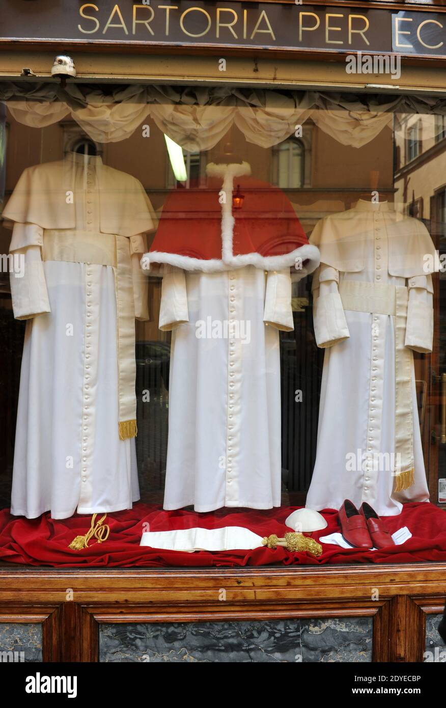 Il minuscolo e vecchio negozio 'Gammarelli' nel centro di Roma, in Italia, ha esposto il 4 marzo 2013 le tre serie di paramenti bianchi da spedire in Vaticano per il nuovo papa. Qui sono state realizzate tre versioni, piccole, medie e grandi dei paramenti bianchi che il nuovo papa indosserà quando apparirà per la prima volta al mondo. 'Gammarelli', come è conosciuta la casa di moda ecclesiastica, ha vestito i capi spirituali della Chiesa Cattolica Romana dal 1798. "Abbiamo preparato tre paramenti in lana bianca, una stola, loschi rossi, un cappuccio coprioggetto, nonché un capo in velluto rosso con bordo in pelliccia bianca, dal momento che è wi Foto Stock