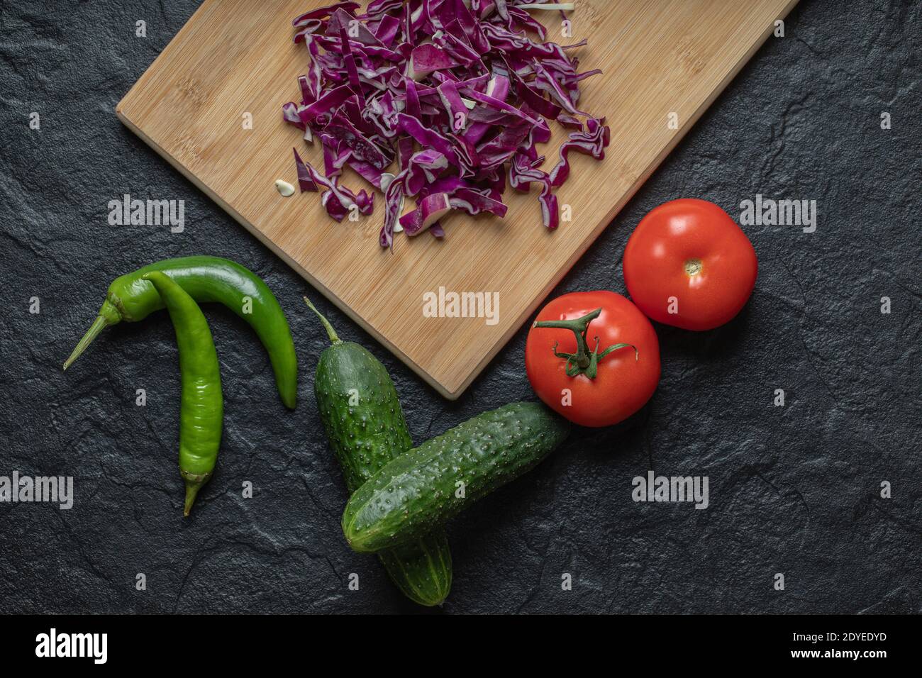 Verdure miste. Cavolo tritato, cetriolo, pomodoro e poppino su fondo nero Foto Stock