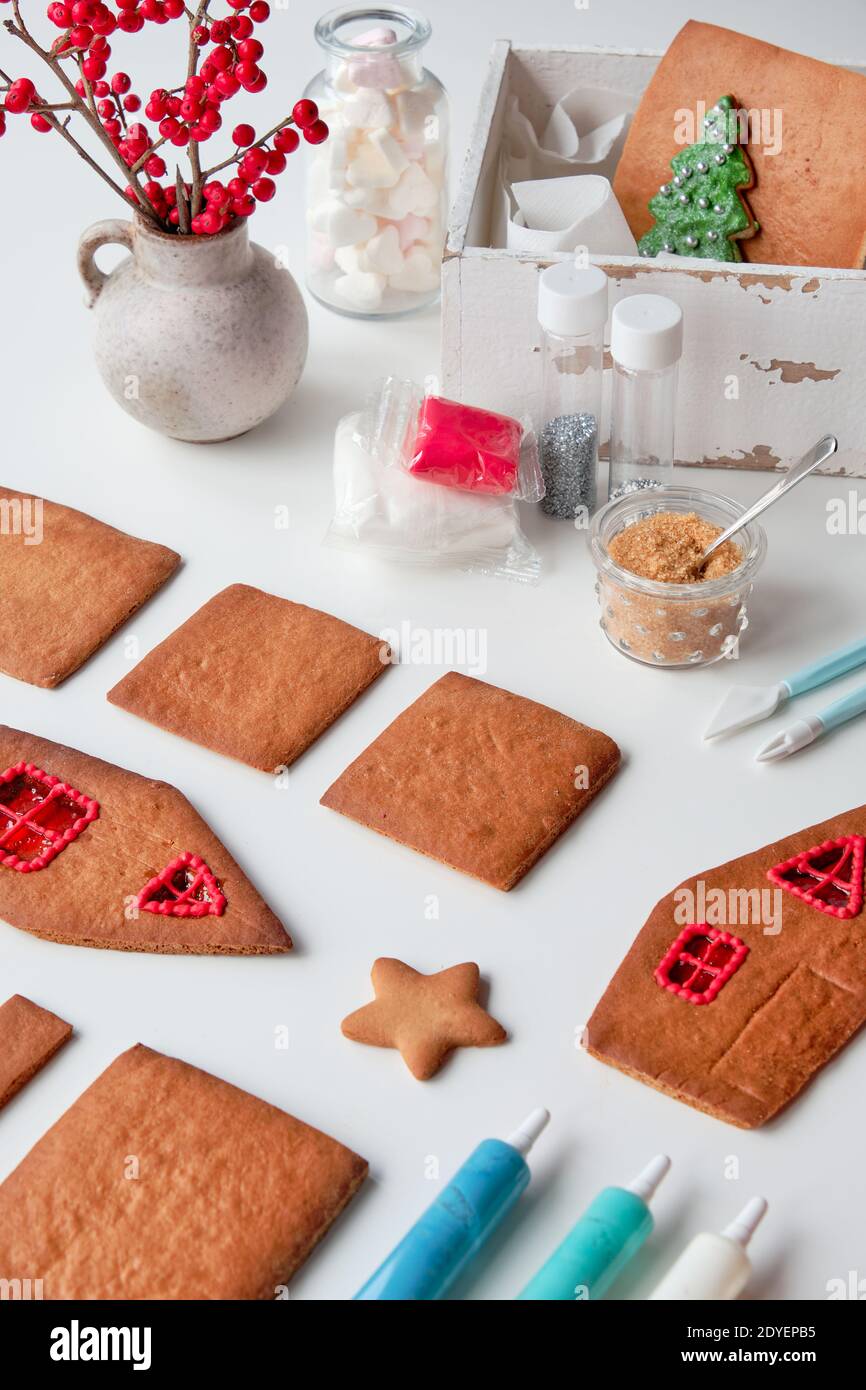 Realizzazione di casa di pan di zenzero, dettagli al forno disposti su sfondo bianco. Natale sfondo festivo. Buon Natale. Foto Stock