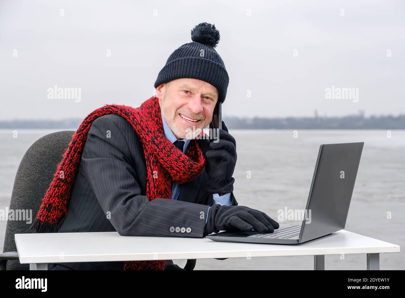 uomo d'affari anziano con la bearded grigia in tuta, sorridente mentre parla sullo smartphone Foto Stock