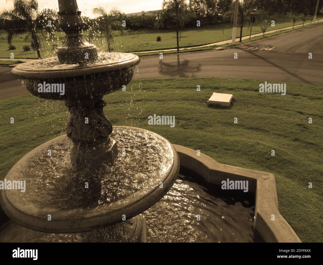 Moderna fontana posta in una piazza pulita con strade vuote [Colori seppia] Foto Stock