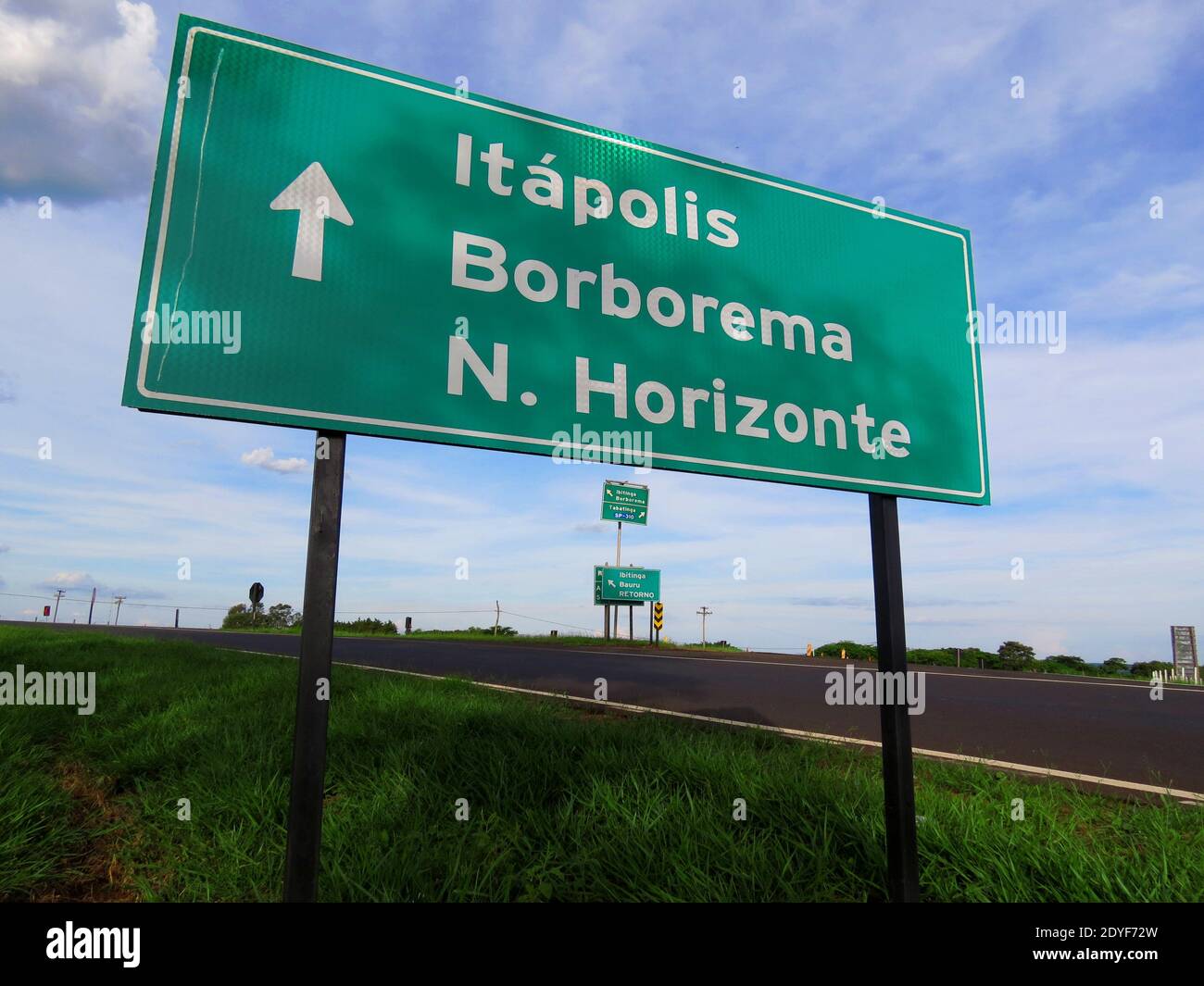 Piastra metallica che dà la direzione di tre città (nomi visualizzati in portoghese) con una grande freccia bianca posizionata sul lato di un percorso di campagna Foto Stock