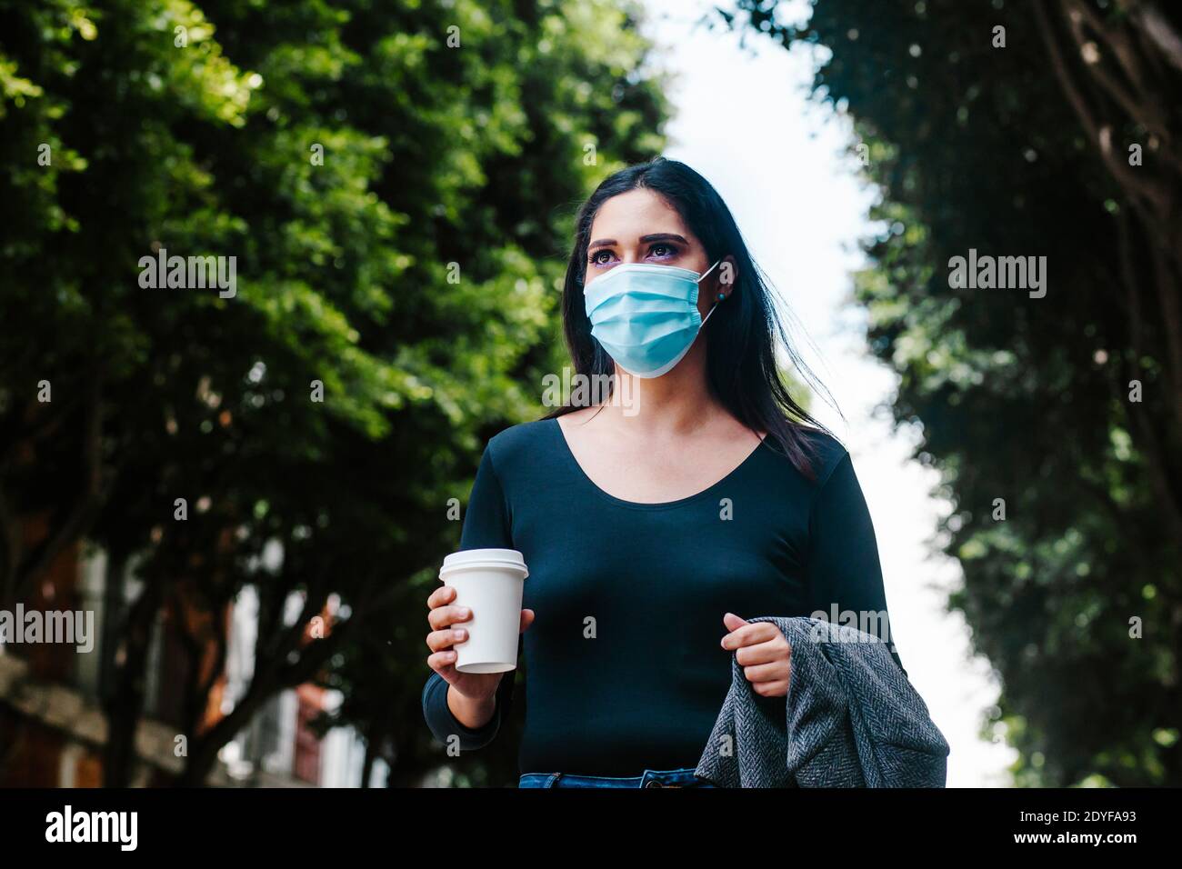 Ritratto di donna di affari messicana con maschera facciale nel strade in una città coloniale dell'america latina per coronavirus pandemia Foto Stock