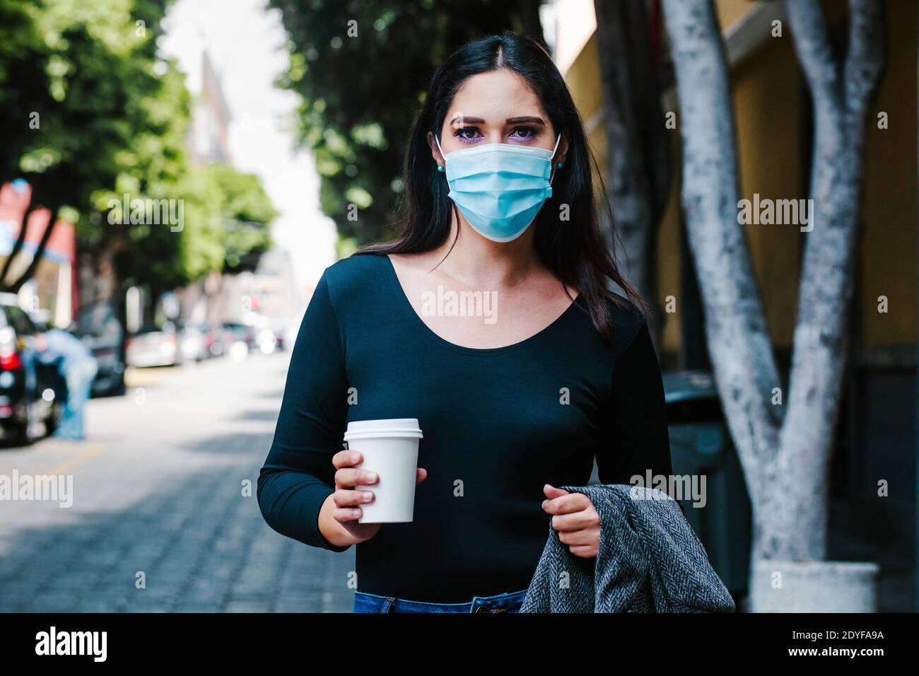 Ritratto di donna di affari messicana con maschera facciale nel strade in una città coloniale dell'america latina per coronavirus pandemia Foto Stock