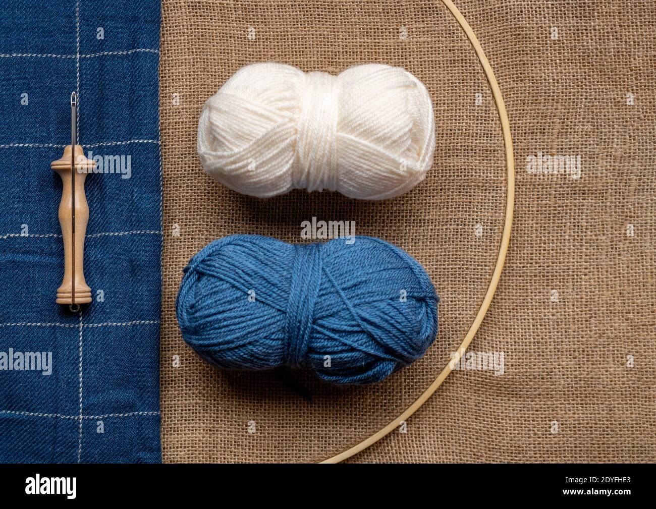 Copia la composizione dello spazio con due palle di lana e un legno punzonare l'ago su un tessuto a tela e un blu coperta Foto Stock