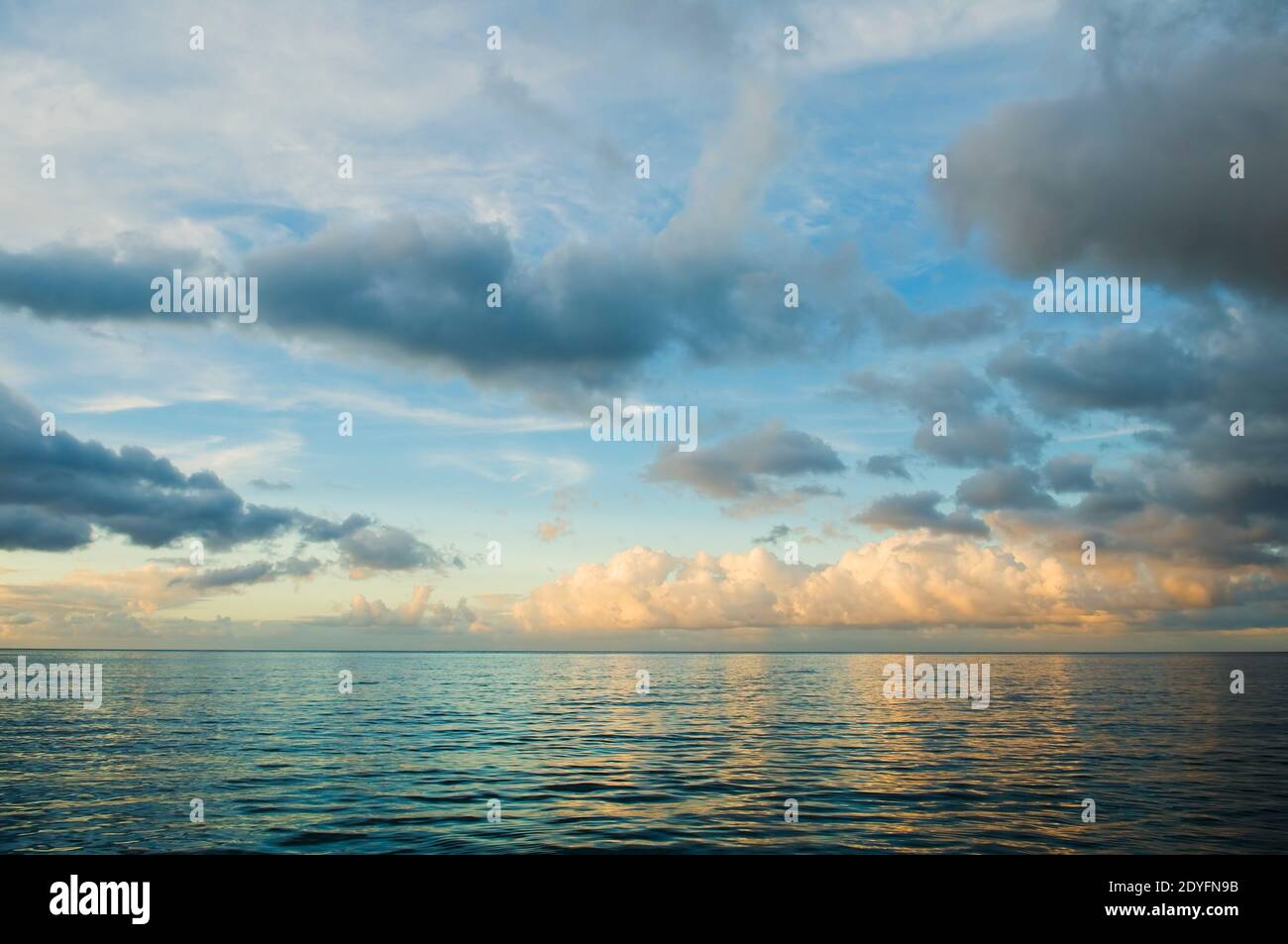 Tramonto sul Mar dei Caraibi. Vista sull'oceano con onde e nuvole. Rilassante mare, sfondo di acque tropicali. Mare blu e riflesso d'oro del do Foto Stock